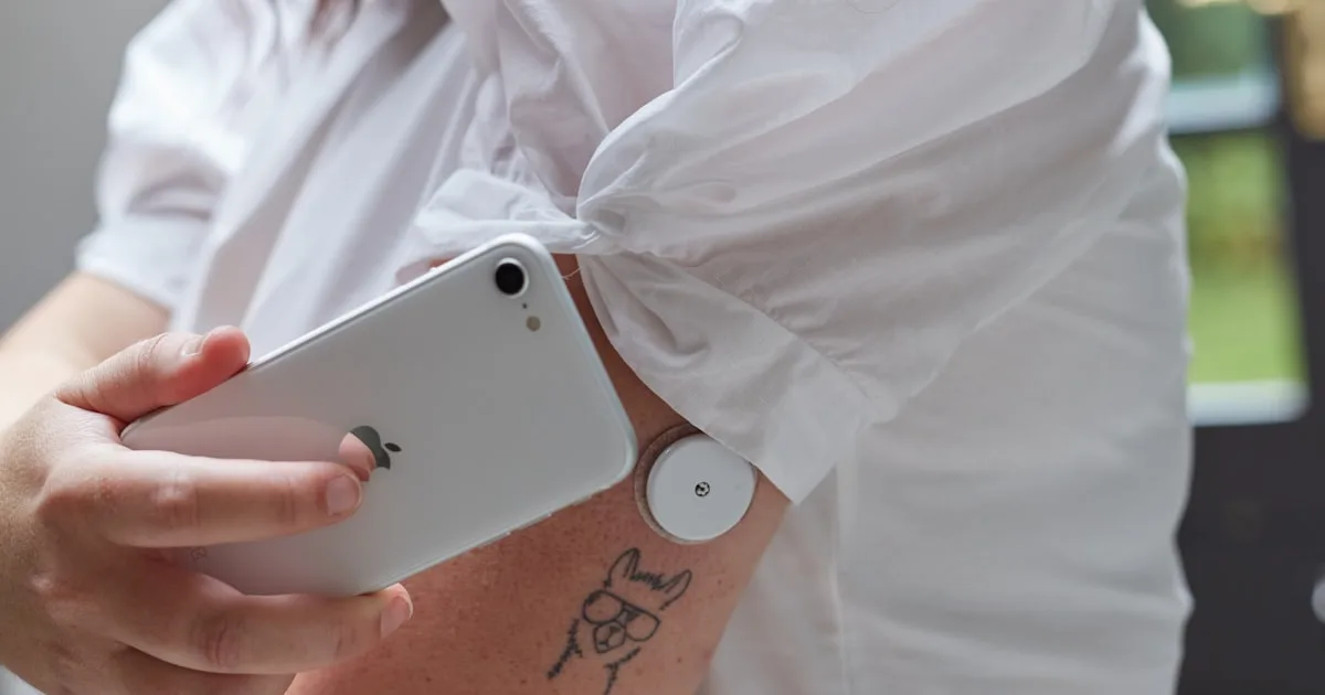 Person scanning a continuous glucose monitor sensor on their upper arm